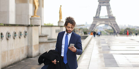 Businessman with smartphone near Eiffel Tower